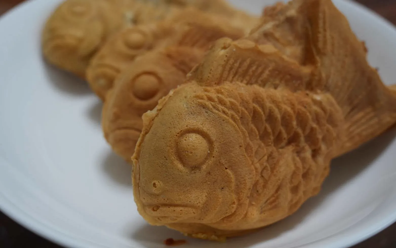 Golden-brown fish-shaped taiyaki pastries on a white plate