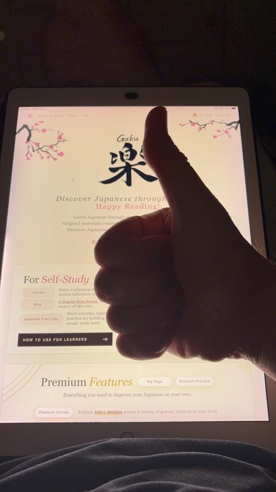 A thumbs-up in front of a tablet displaying the Gaku website