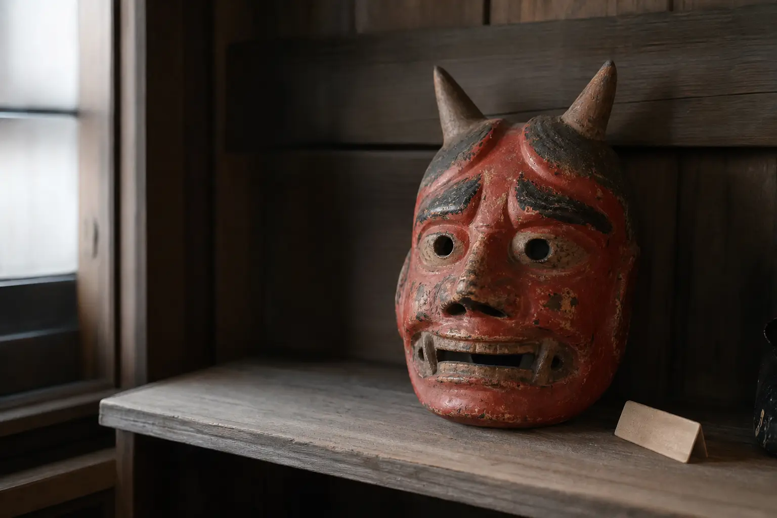 Traditional Japanese oni mask displayed on a wooden shelf